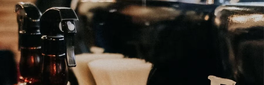 Close view of brown barber spray bottles and white shaving brushes on a black counter
