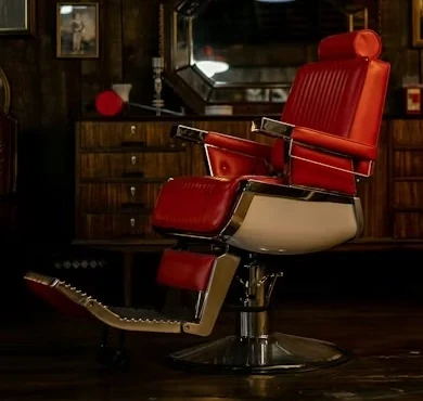 Close view of a red leather and chrome barber chair with its footrest