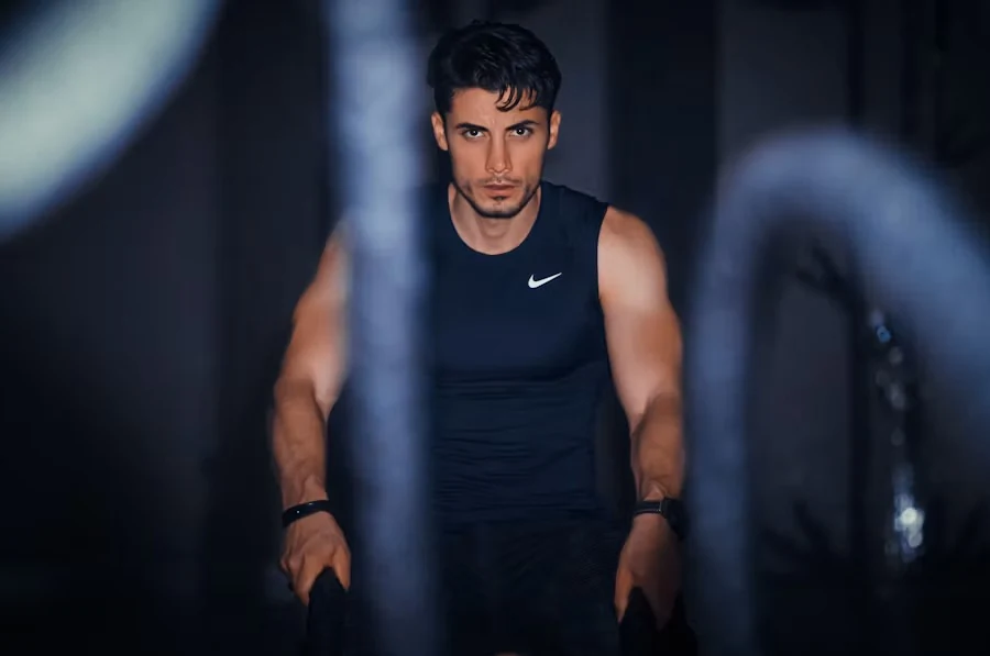 Coach in a dark sleeveless top standing between heavy battle ropes