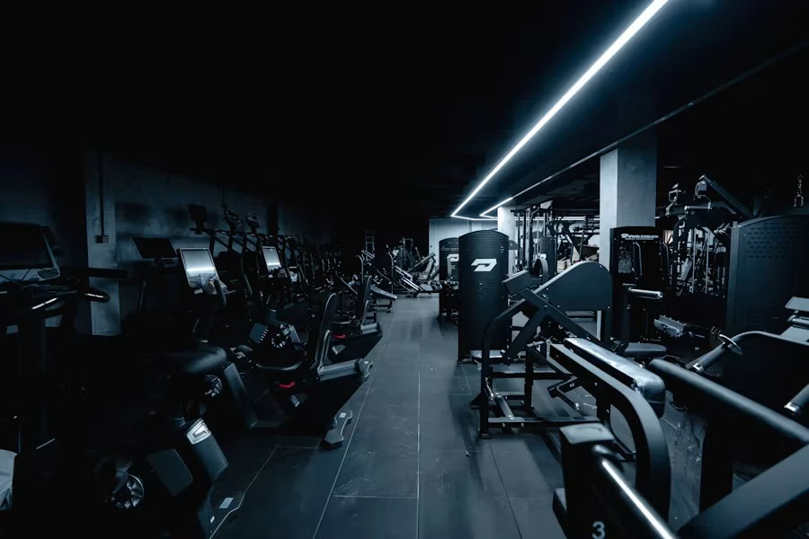 Dim weights floor lit by a neon strip, with rows of machines and benches