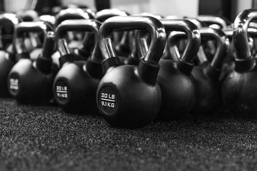 Rows of black kettlebells on rubber flooring, in black and white