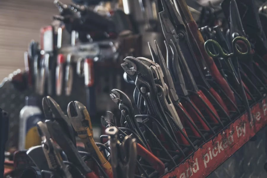 Rows of pliers and wrenches with red handles stacked on a rack