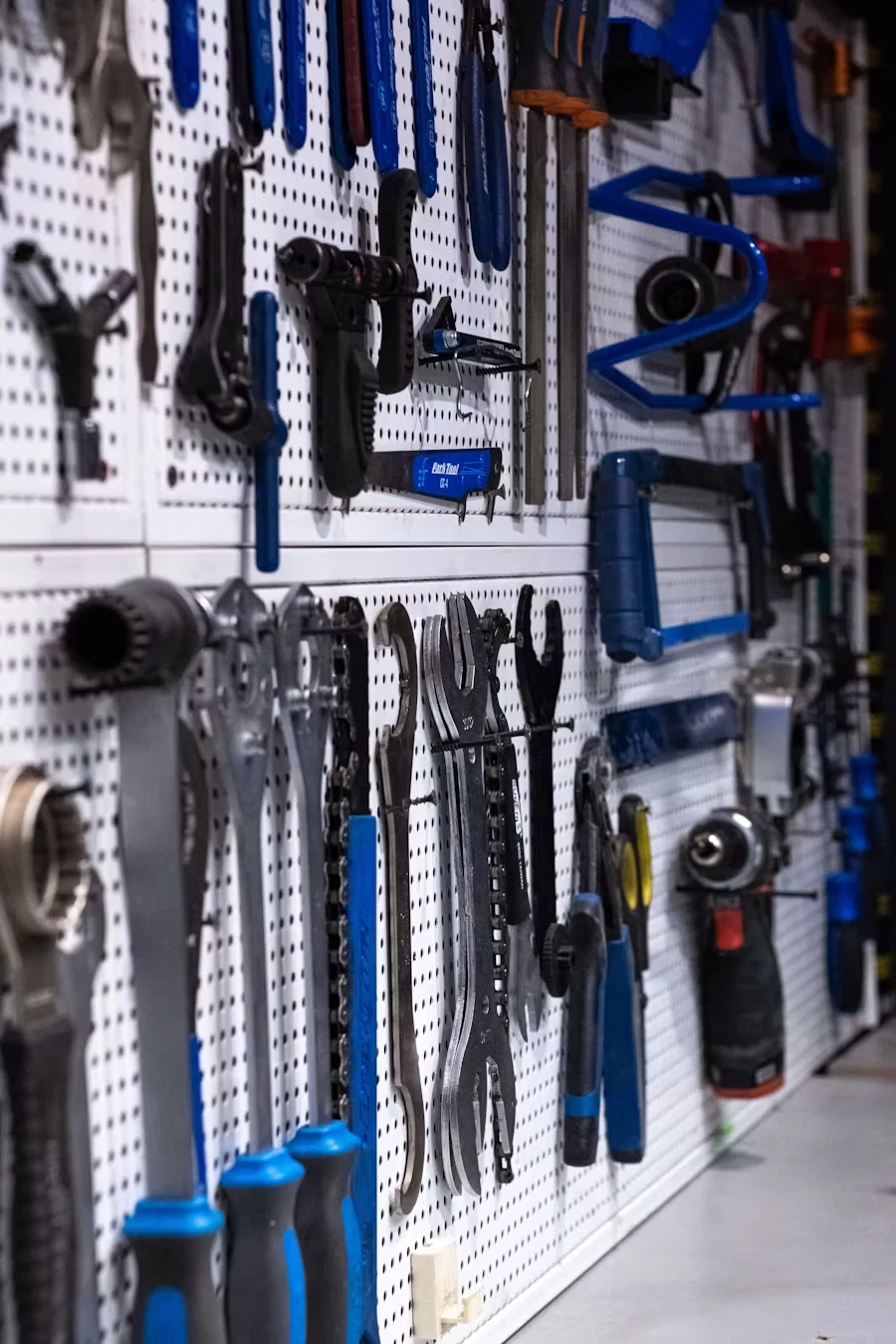 A white pegboard wall hung with blue-handled wrenches, pipe tools and clamps