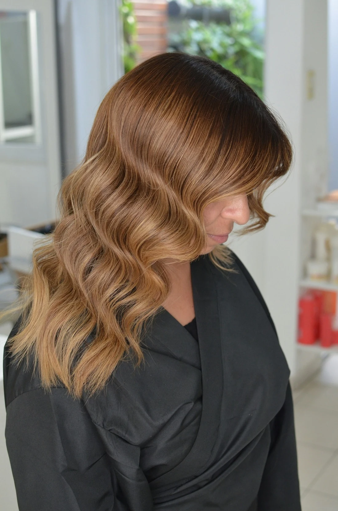 A client in profile with caramel balayage waves