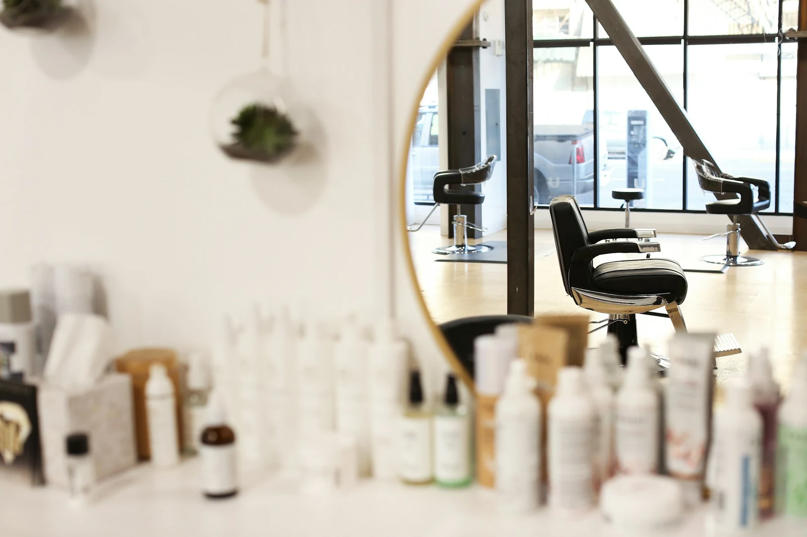 Hair and skin care bottles on a white counter in front of a salon mirror