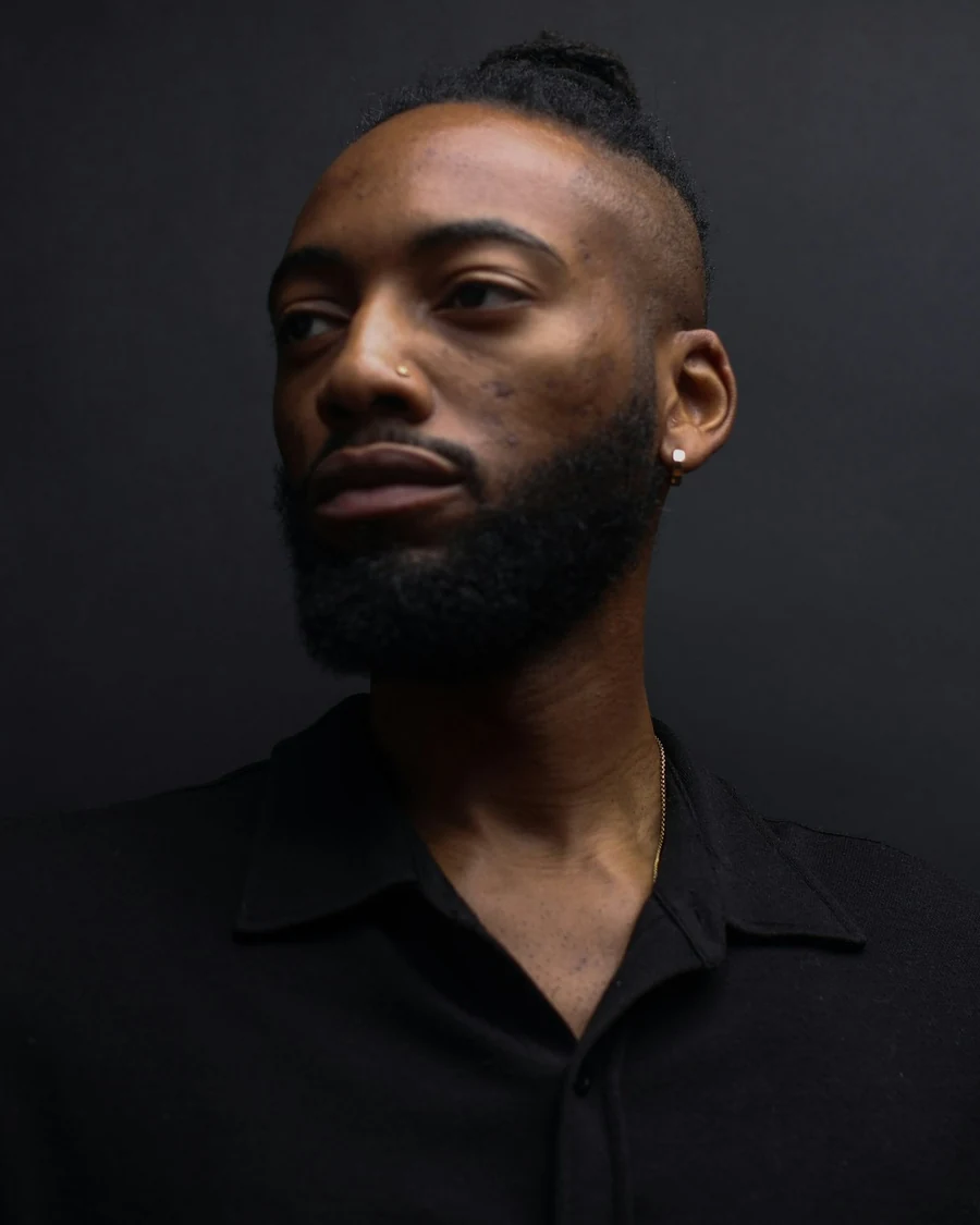 Portrait of a bearded stylist in a black shirt against a dark backdrop